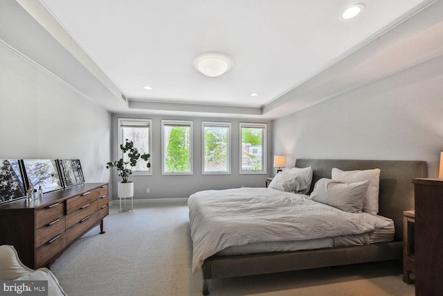bedroom featuring baseboards, a raised ceiling, light carpet, and multiple windows