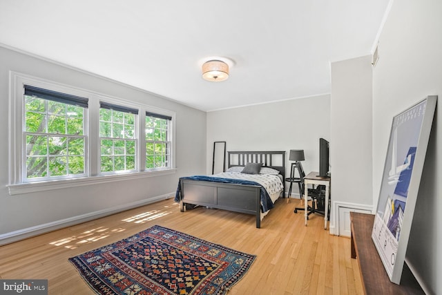 bedroom featuring crown molding, hardwood / wood-style floors, and baseboards