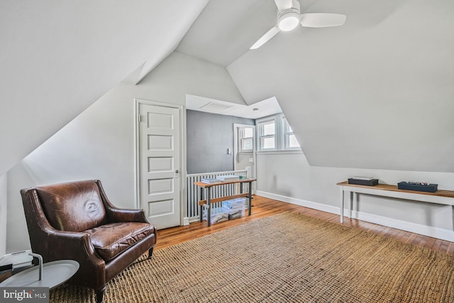 living area featuring wood finished floors, a ceiling fan, visible vents, baseboards, and lofted ceiling