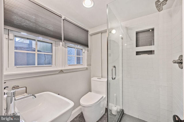 full bath featuring a sink, a shower stall, toilet, baseboards, and tile patterned flooring