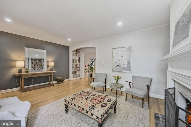 living area with a fireplace with flush hearth, wood finished floors, baseboards, and arched walkways