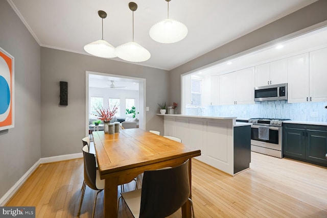 kitchen with tasteful backsplash, stainless steel appliances, light wood finished floors, white cabinetry, and a peninsula