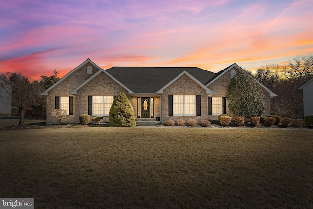 view of front of property with a lawn and brick siding