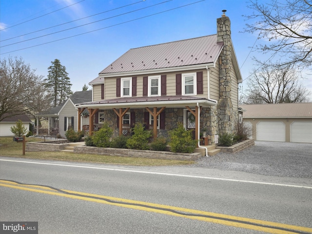 view of front facade featuring a porch, a chimney, an outdoor structure, a garage, and stone siding