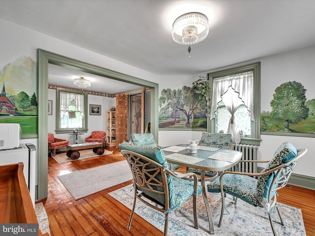 dining area with wood-type flooring, radiator, and a chandelier