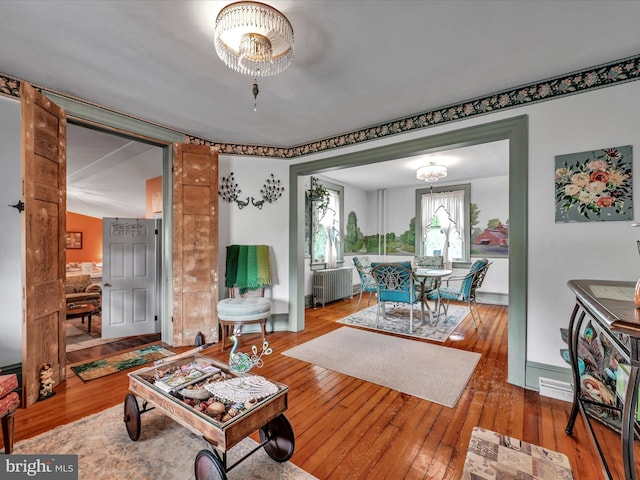 living room with radiator heating unit, baseboards, and wood-type flooring