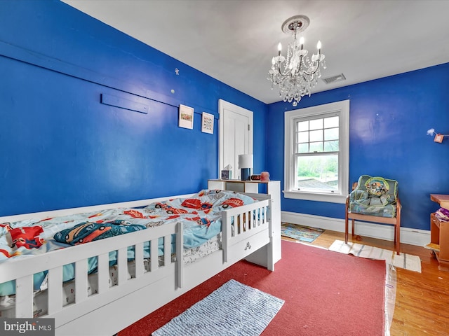 bedroom featuring visible vents, wood finished floors, baseboards, and a chandelier