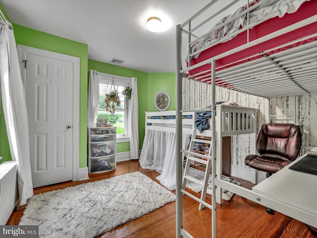 bedroom featuring radiator heating unit, wood finished floors, and visible vents