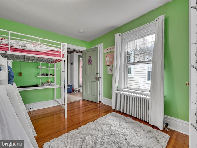 bedroom featuring radiator, baseboards, and wood finished floors