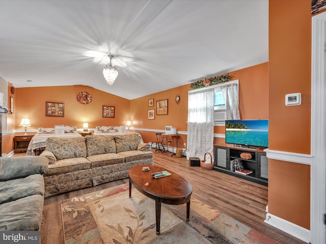 living area with cooling unit, wood finished floors, an inviting chandelier, and vaulted ceiling