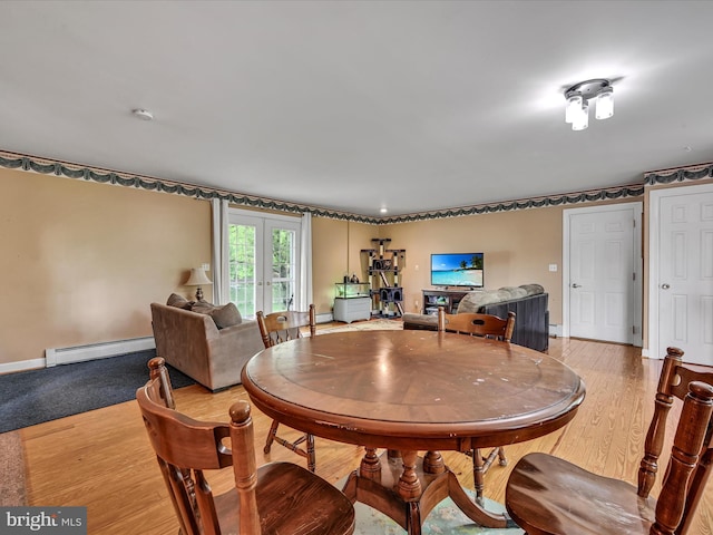 dining area featuring a baseboard heating unit, light wood-style flooring, french doors, and baseboards