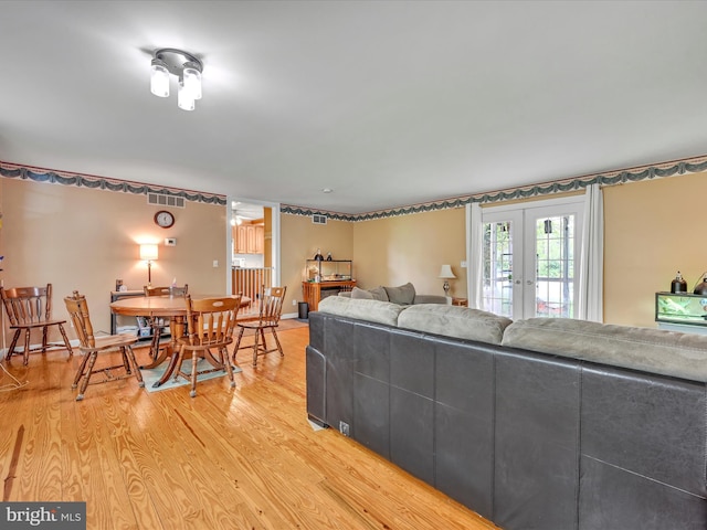 living area with french doors, baseboards, visible vents, and light wood-style flooring