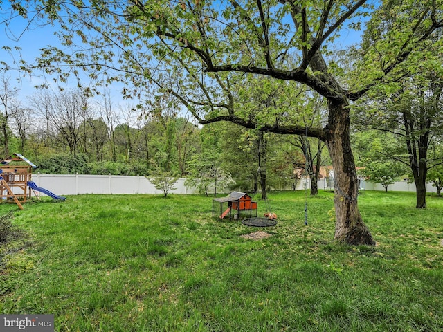 view of yard featuring an outbuilding, a playground, fence, and exterior structure