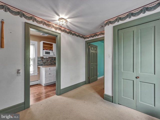 bedroom with a baseboard radiator, baseboards, light colored carpet, and visible vents