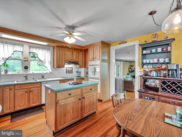 kitchen with a ceiling fan, a sink, a kitchen island, white dishwasher, and light wood finished floors