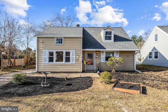 view of front of house with a vegetable garden, fence, and a shingled roof