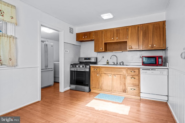 kitchen featuring a sink, refrigerator, light countertops, dishwasher, and stainless steel gas range