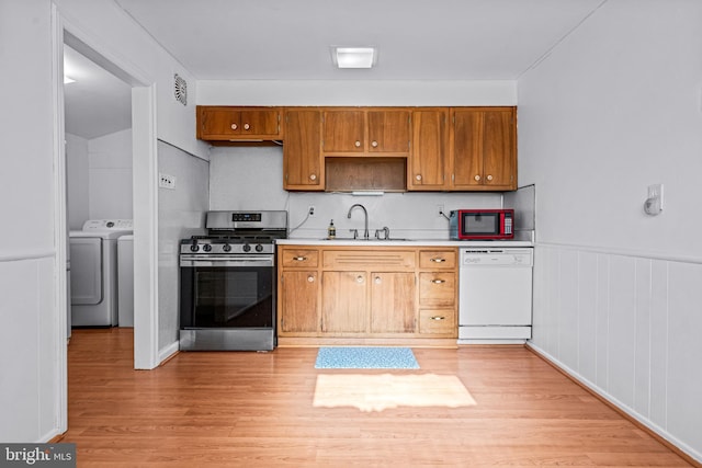 kitchen featuring a sink, light wood-style floors, white dishwasher, light countertops, and gas range