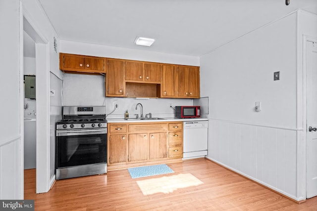 kitchen with stainless steel range with gas stovetop, dishwasher, light countertops, light wood-style floors, and a sink