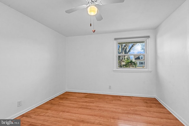 spare room featuring a ceiling fan, light wood-type flooring, and baseboards