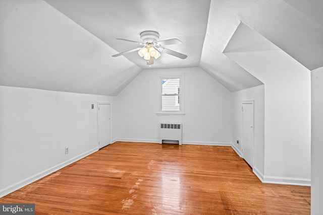 additional living space featuring vaulted ceiling, radiator heating unit, wood finished floors, and baseboards