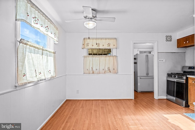 kitchen featuring visible vents, brown cabinets, a ceiling fan, light wood-style floors, and appliances with stainless steel finishes