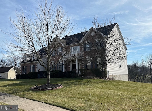 view of front of home featuring brick siding, a balcony, and a front yard