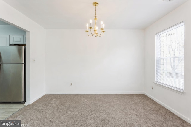 spare room featuring a chandelier, visible vents, light colored carpet, and baseboards