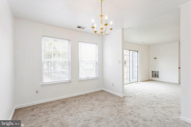 spare room with a chandelier, visible vents, a wealth of natural light, and carpet floors