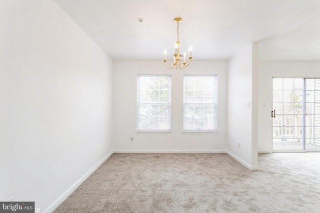 carpeted empty room with baseboards, plenty of natural light, and a notable chandelier