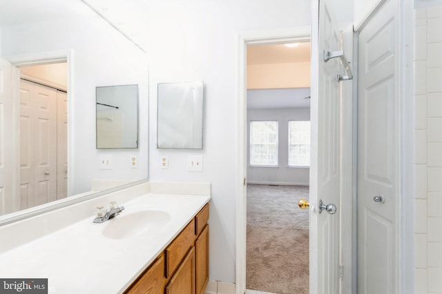 bathroom with a closet, baseboards, and vanity