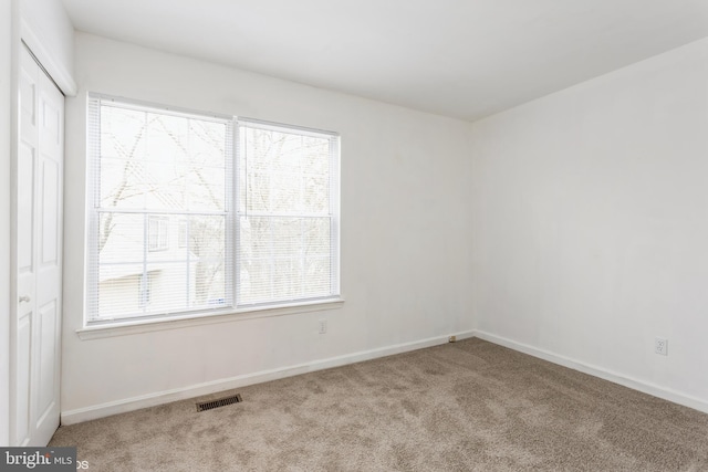 carpeted spare room featuring baseboards and visible vents