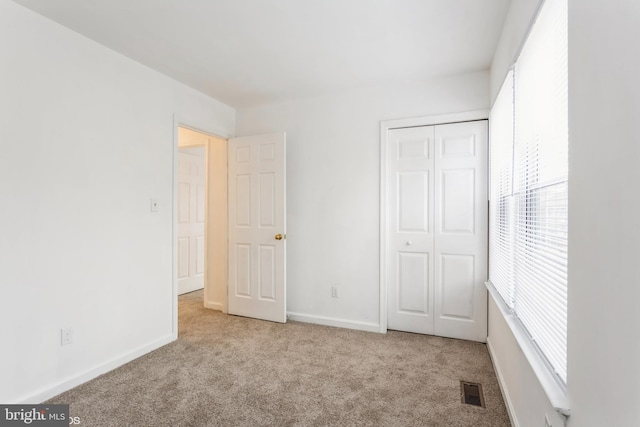 unfurnished bedroom with a closet, visible vents, baseboards, and carpet