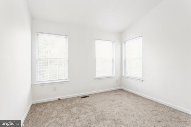 empty room featuring baseboards, visible vents, carpet floors, and lofted ceiling