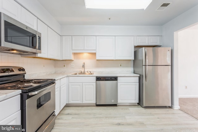 kitchen with a sink, white cabinets, visible vents, and stainless steel appliances