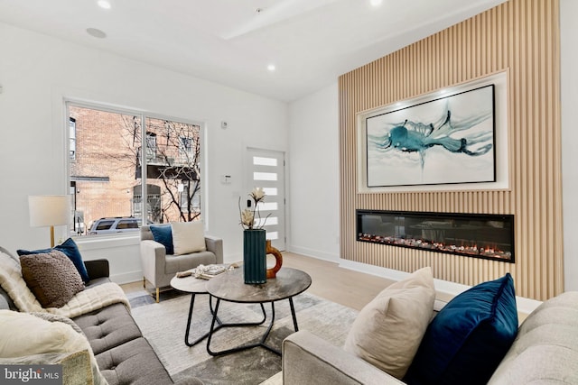 living room featuring recessed lighting, a healthy amount of sunlight, and a glass covered fireplace