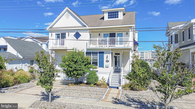 view of front of home featuring a balcony, driveway, and a shingled roof