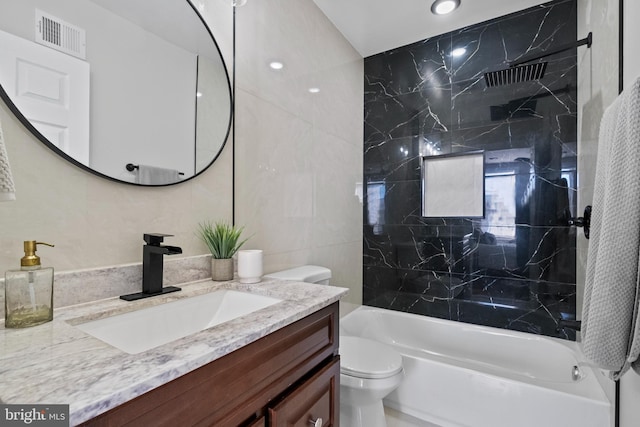 full bath featuring vanity, visible vents, shower / bath combination, tile walls, and toilet