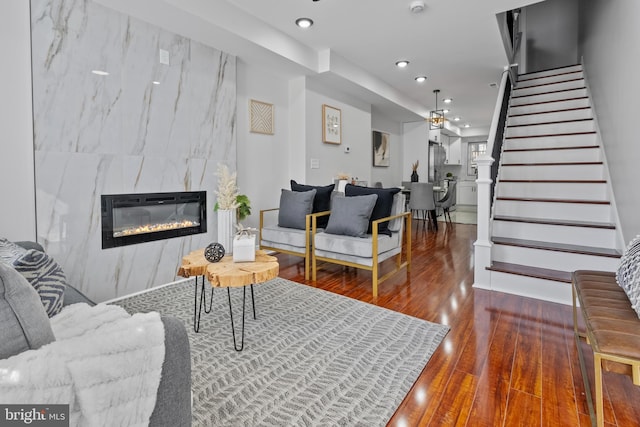 living area with a high end fireplace, recessed lighting, stairs, and wood finished floors