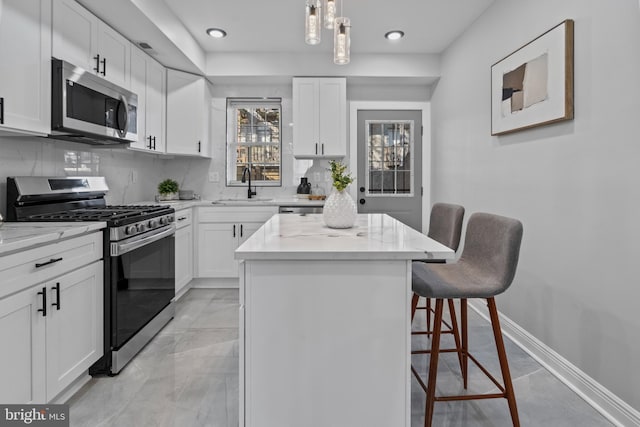 kitchen featuring tasteful backsplash, a breakfast bar, stainless steel appliances, white cabinetry, and a sink