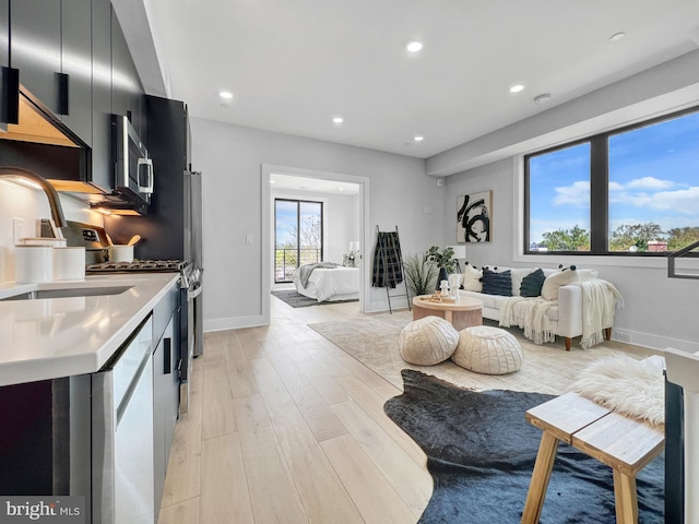 kitchen with open floor plan, light countertops, dark cabinetry, stainless steel appliances, and a sink