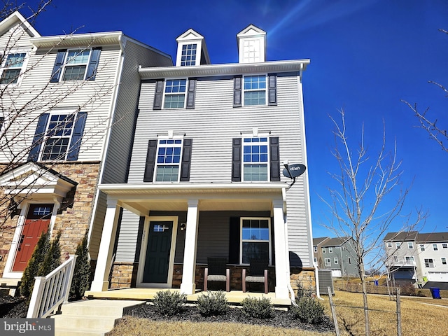 view of front of home featuring a porch, central AC unit, and stone siding