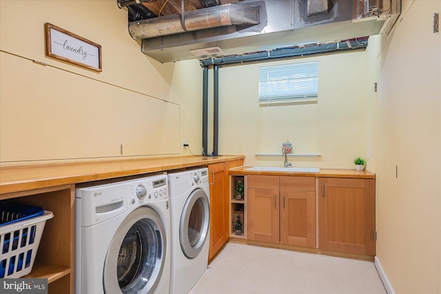 washroom with cabinet space, washer and dryer, and a sink