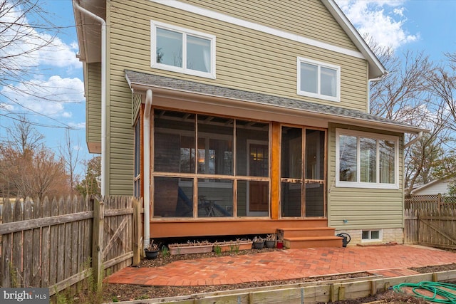 rear view of property featuring a patio, fence, and a sunroom