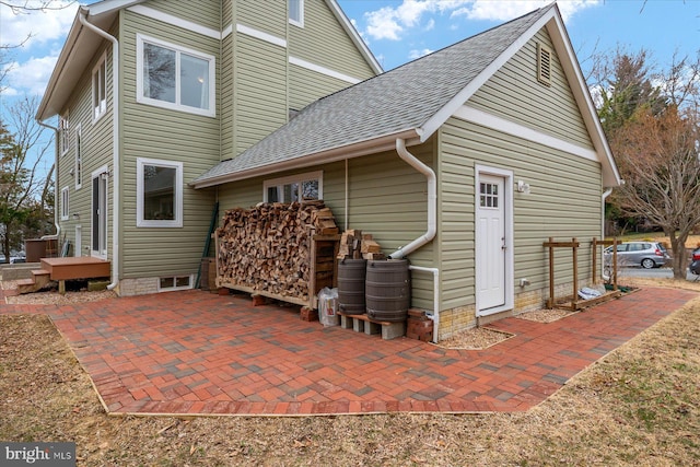 rear view of house with a patio area and a shingled roof