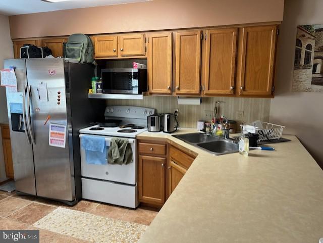 kitchen featuring a sink, brown cabinets, appliances with stainless steel finishes, and light countertops