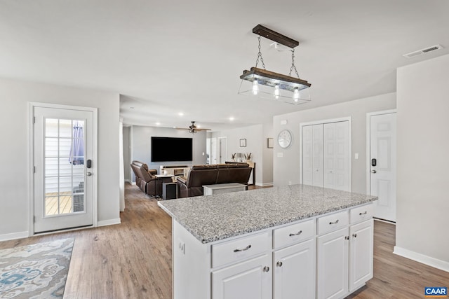 kitchen featuring white cabinetry, a center island, visible vents, and light wood-type flooring