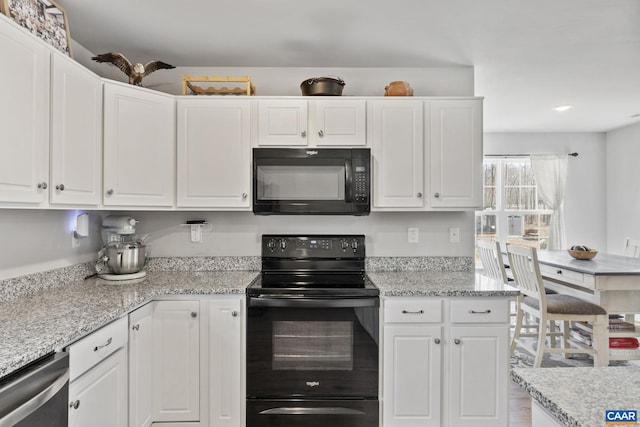 kitchen with white cabinetry, black appliances, and light stone countertops