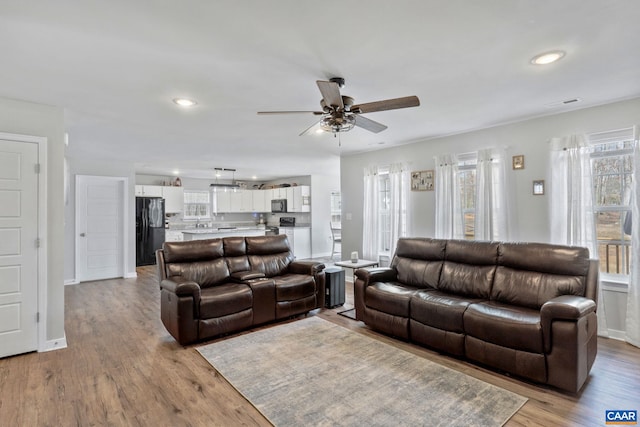 living room with recessed lighting, visible vents, light wood finished floors, and baseboards