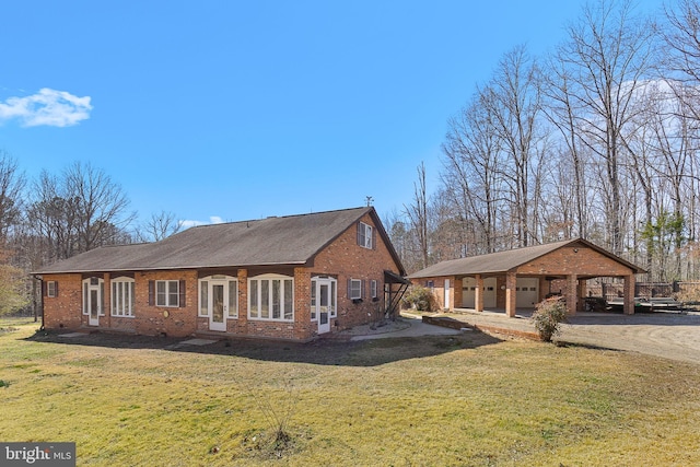 view of front facade featuring a front yard, driveway, an outdoor structure, french doors, and brick siding